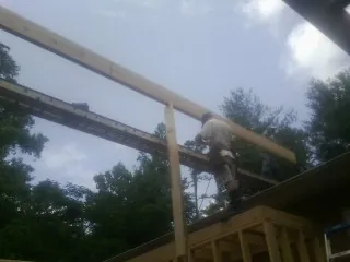 Carpenter setting a ridge beam over a new addition frame — Ice Dam Removal by Roofing Brothers in Piermont