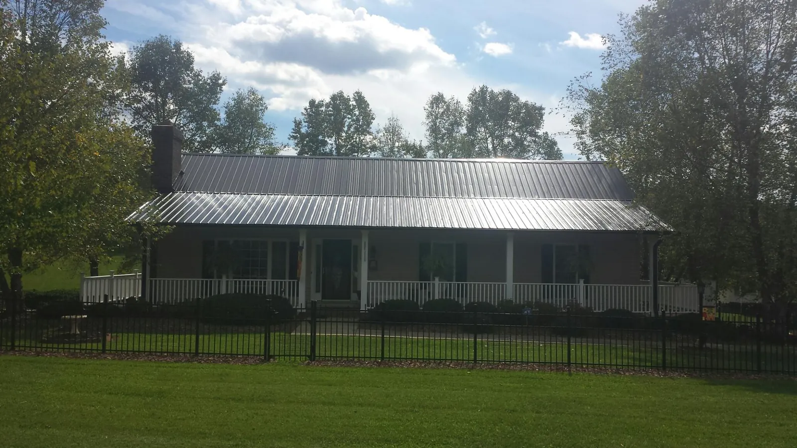 Gray metal roof on a brick ranch with a full width front porch — Gutter Guard Installation work by our crew in Piermont