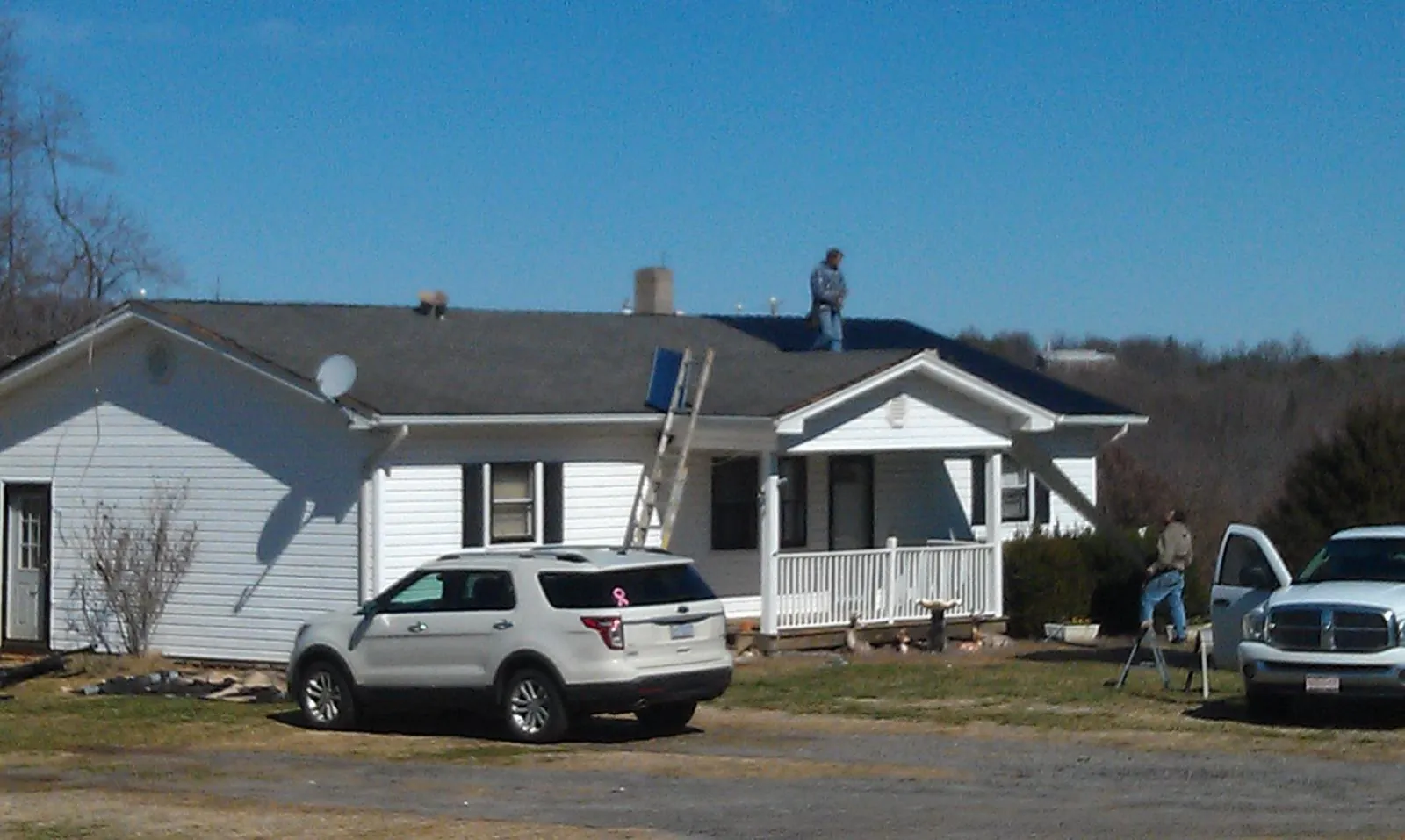 Roofers stripping shingles from a white ranch house roof in Piermont